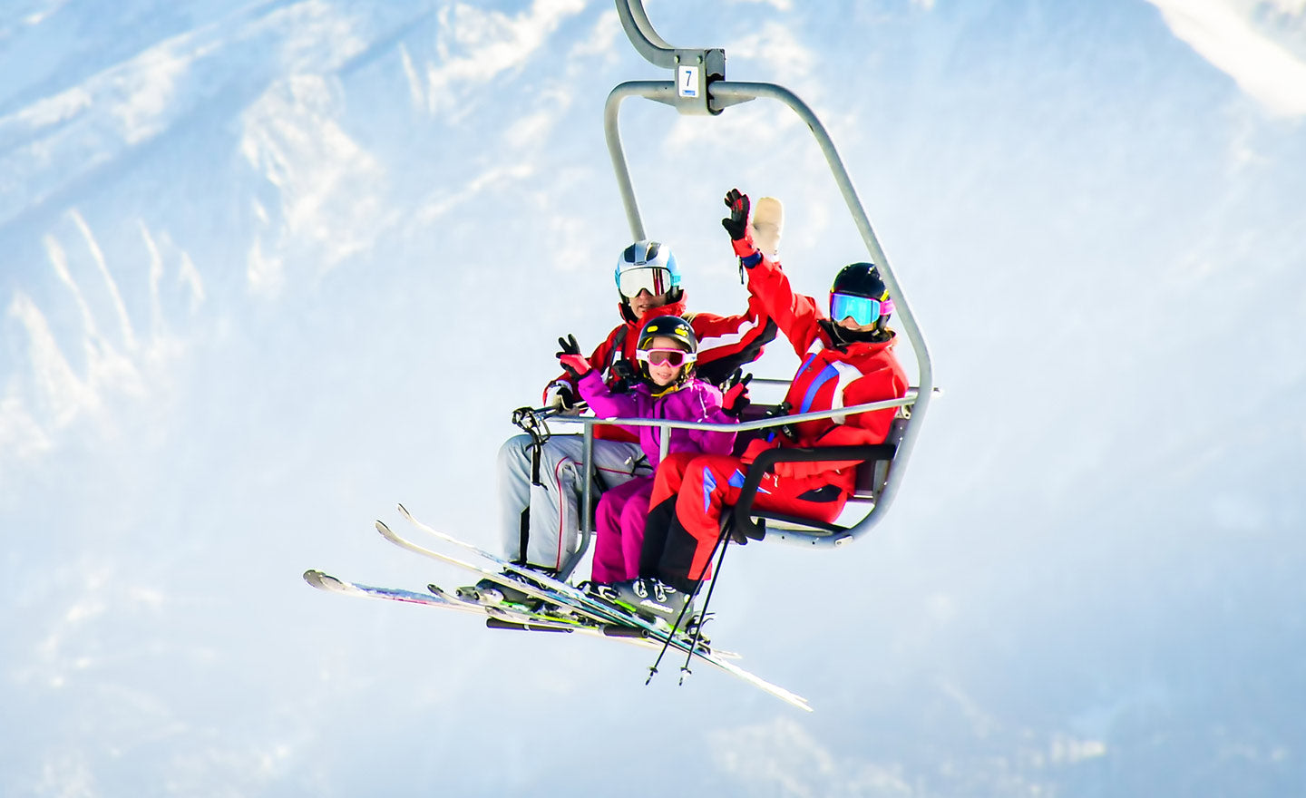 Happy family riding ski chair lift